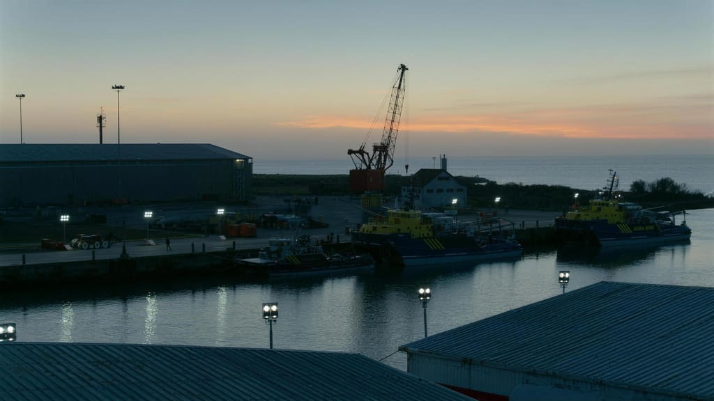 The quay at the operations base at dusk, with workboats alongside and a crane standing over the wharf.